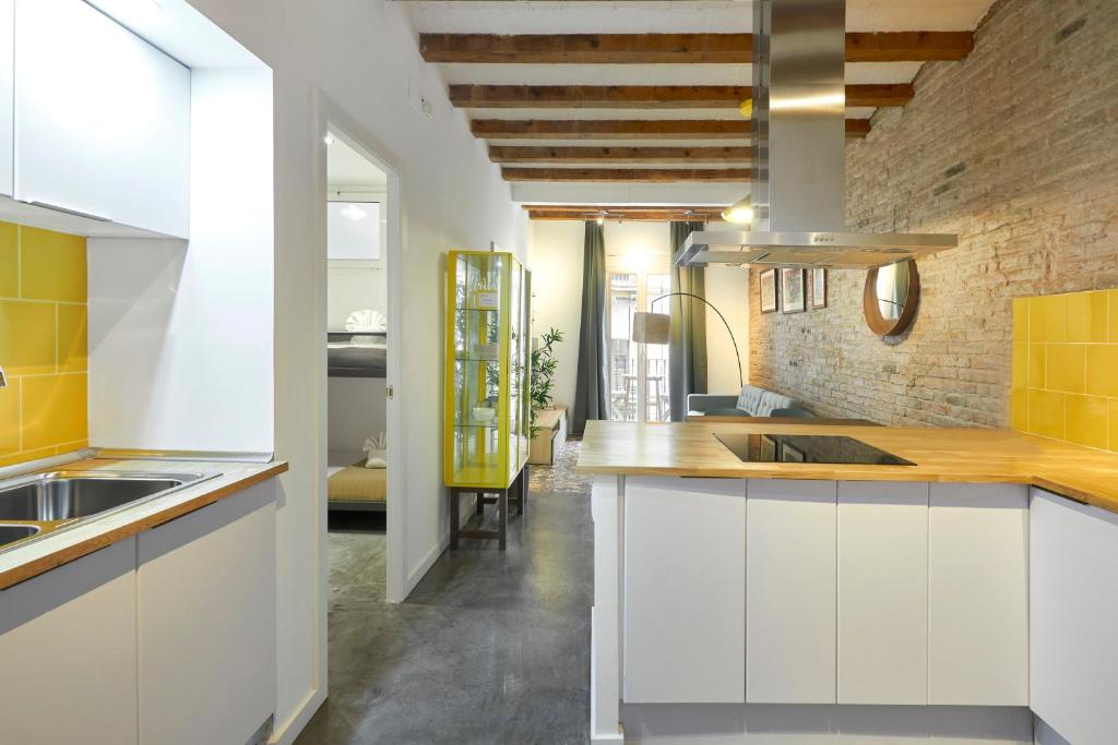 una cocina con armarios blancos y una pared de ladrillo en 64 Apartment in a typical Barcelona's old building, en Barcelona