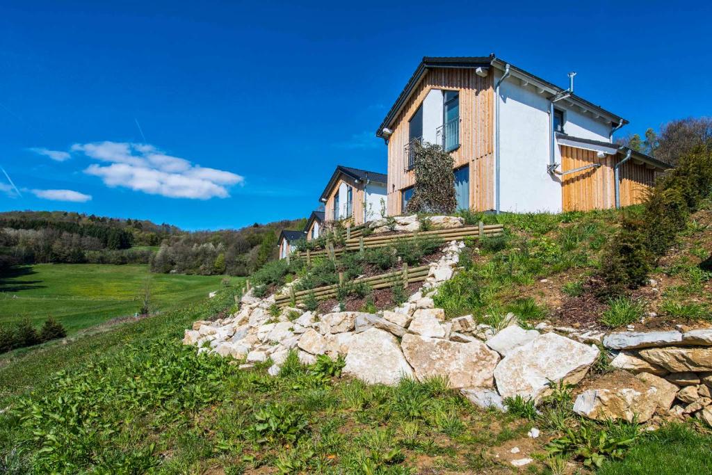 a house on a hill with a stone wall at House and Apt. in Mistelgau-Obernsees 26603 in Obernsees