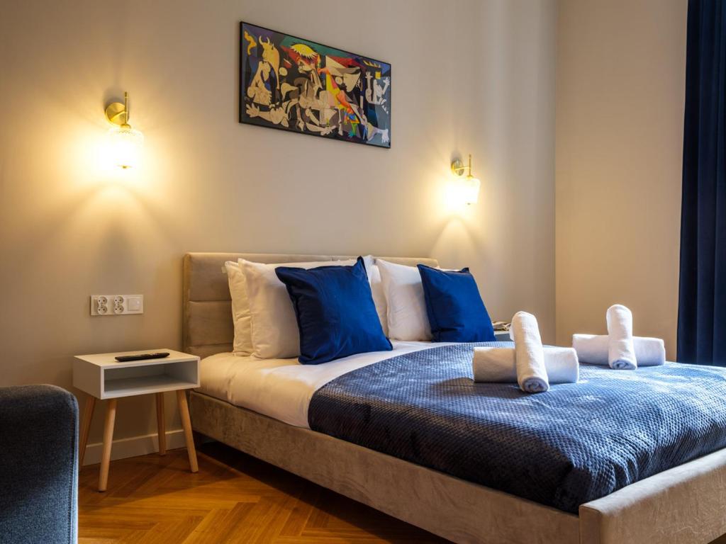 1 dormitorio con 1 cama grande con almohadas azules en Tyzenhauz Suites Topolowa, en Cracovia
