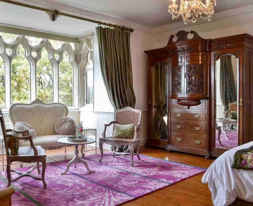 a bedroom with a couch and chairs and a large window at Priory Manor Luxury on Lake Windermere in Windermere