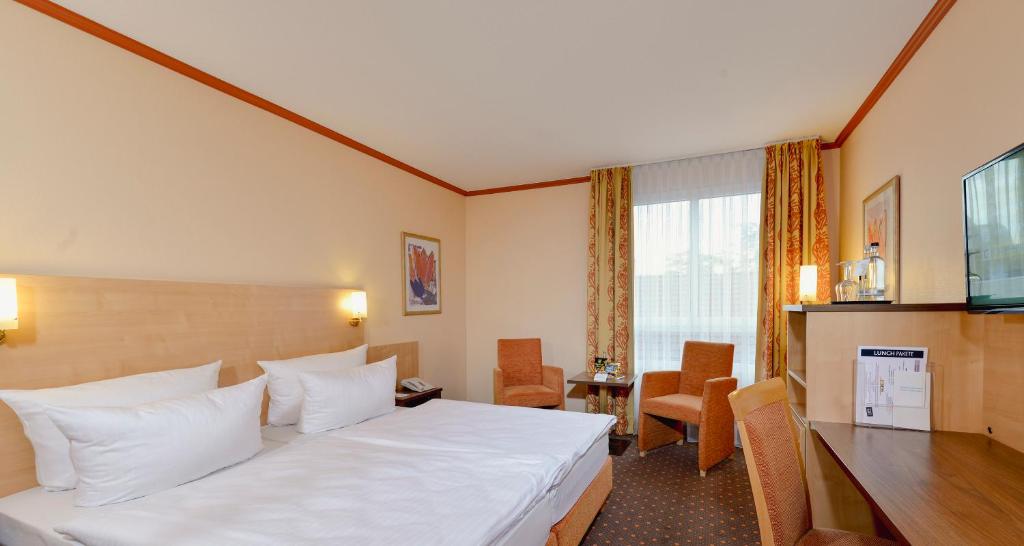 una camera d'albergo con letto bianco e scrivania di Sure Hotel by Best Western Hilden-Düsseldorf a Hilden