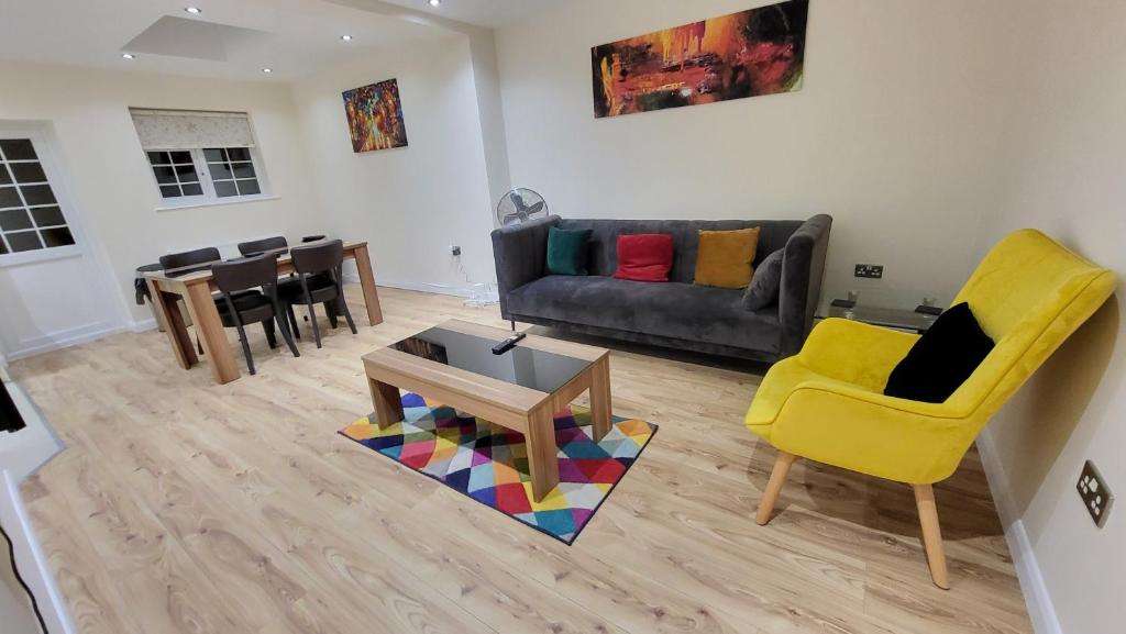 uma sala de estar com um sofá e uma cadeira amarela em Garland Modern Spacious Apartment With Garden em Edgware