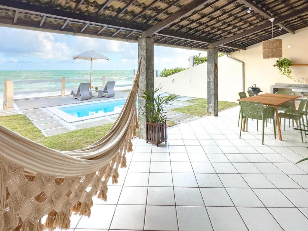 a hammock on a patio with a view of the ocean at Casa Sol Ipioca in Maceió