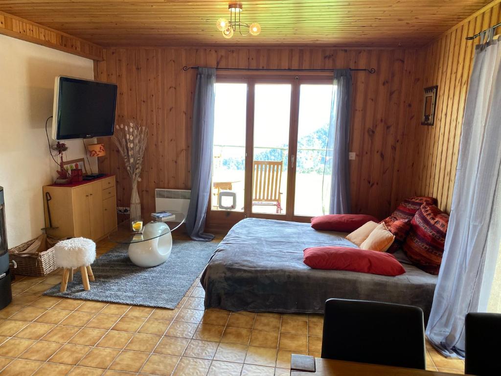 um quarto com uma cama e uma grande janela em Chalet Le Petit Foyer em Salvan