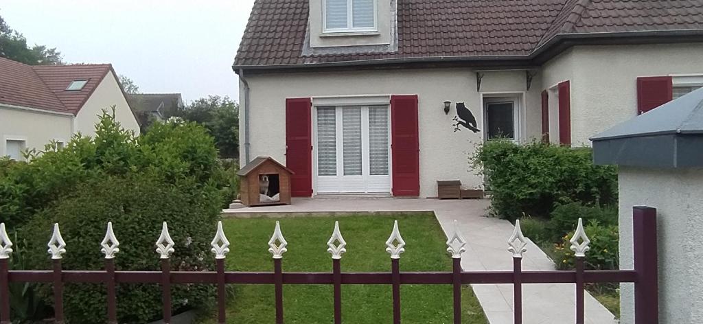 une clôture devant une maison avec un chien dans l'établissement CHOUETTE MAISON, à La Verrière