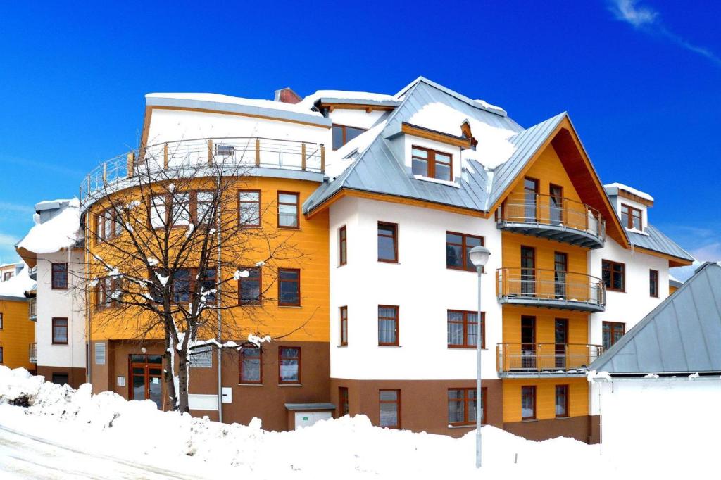 un grand immeuble avec de la neige au sol dans l'établissement Apartments Rokytka 112 a 208, à Rokytnice nad Jizerou