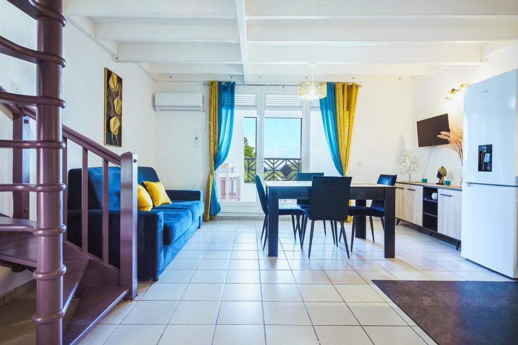 een woonkamer met een blauwe bank en een tafel bij Le Goyave – Bel appartement cosy en résidence in Le Gosier