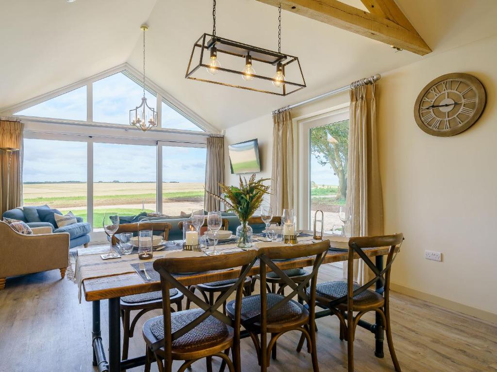 a dining room with a table with chairs and a clock at 1 Pheasant in East Ilsley