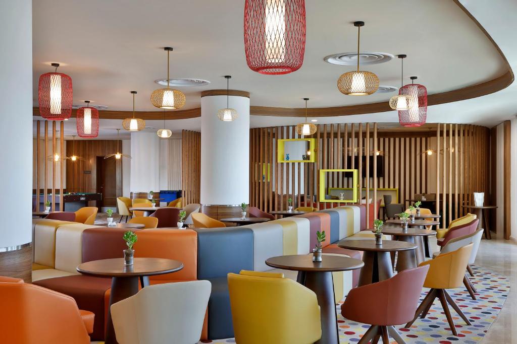 un restaurante con mesas, sillas y luces en Hampton By Hilton Sharma - NC1, en Khuraybah
