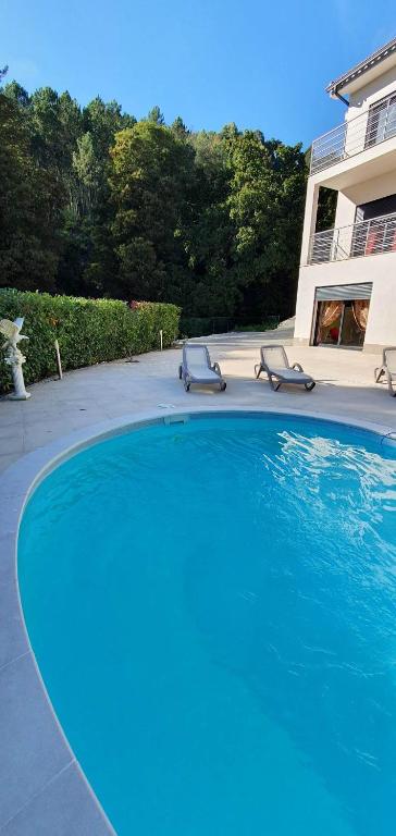 a large swimming pool with two chairs and a house at Casa Ramada in Vilar da Veiga