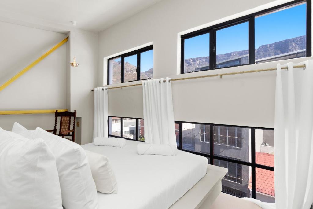 a bedroom with two beds and large windows at Loft on Hope in Cape Town