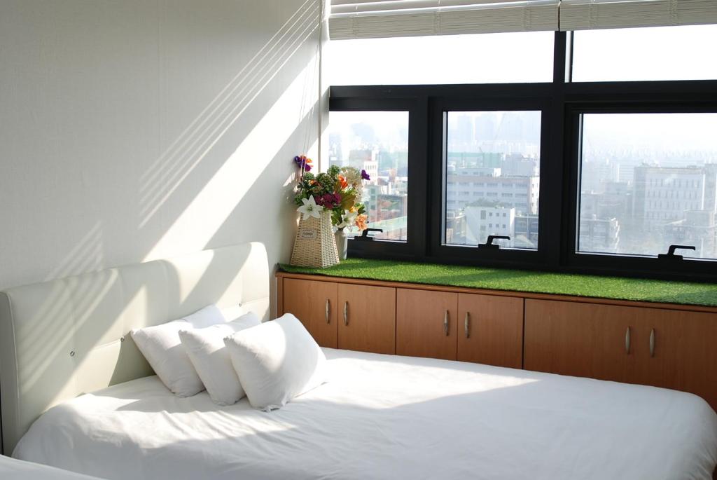 a bedroom with a white bed with a large window at Gangnam Samseong coexmall SS in Seoul