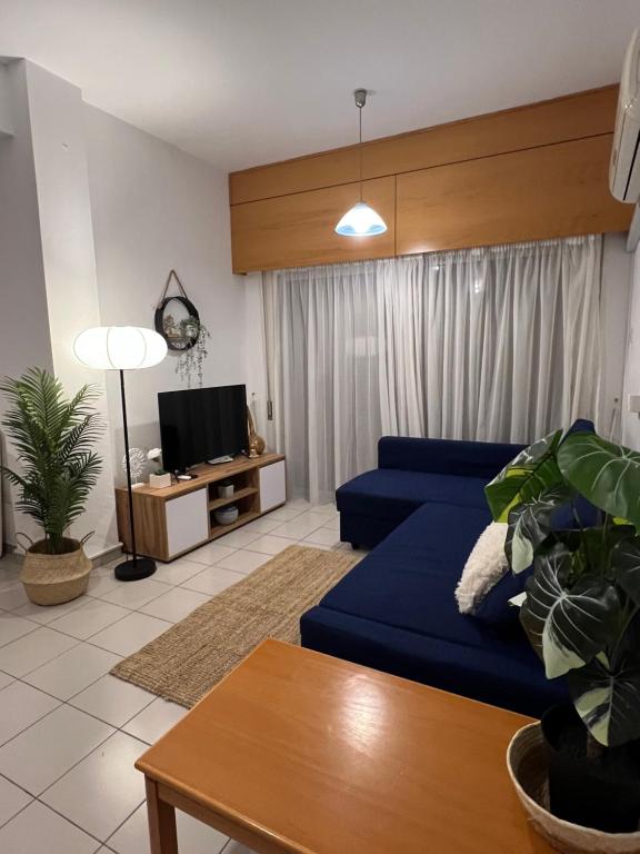 uma sala de estar com um sofá azul e uma televisão em Makenzie 2 rooms em Lárnaca