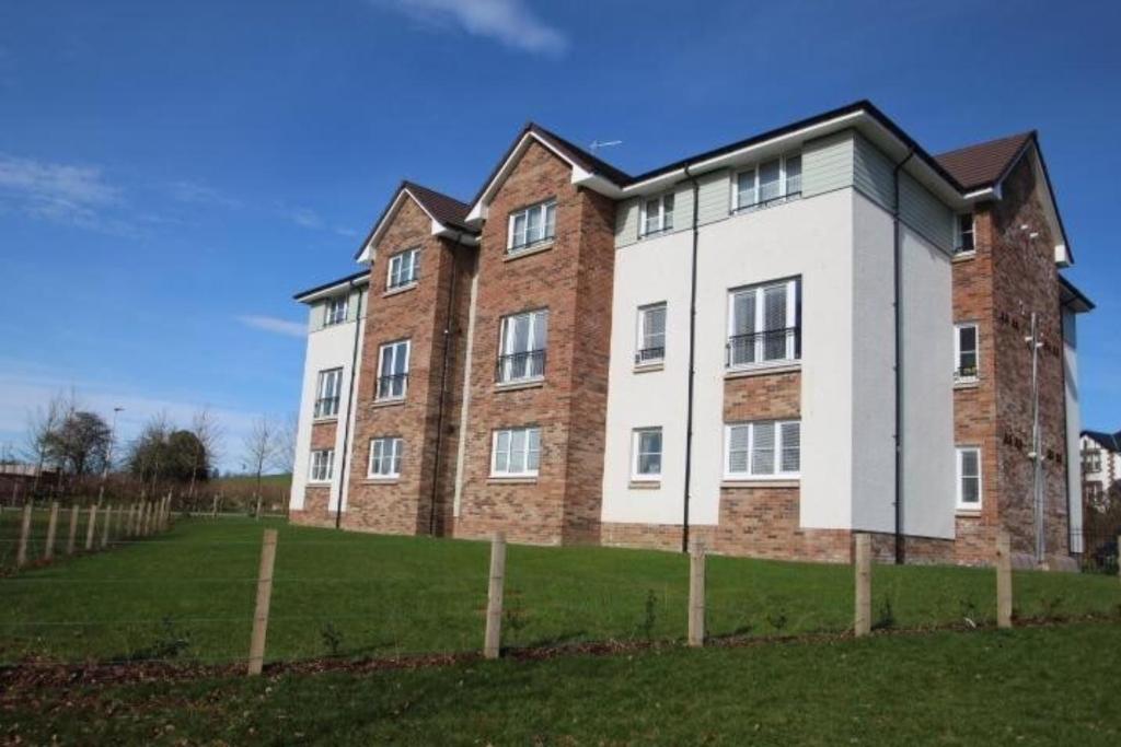 a large brick building on a grassy field at 2 bedroom luxury flat in quiet village of Bishopton in Bishopton
