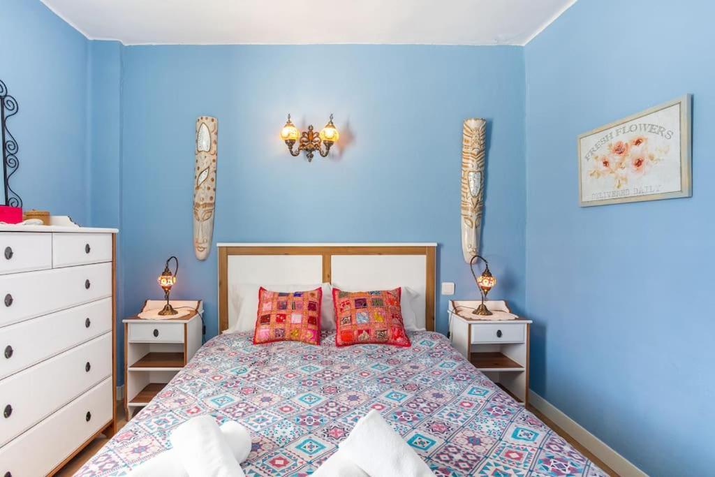 um quarto azul com uma cama e duas mesas de cabeceira em Javea Family Oasis: Steps from the Beach em Platja de l'Arenal
