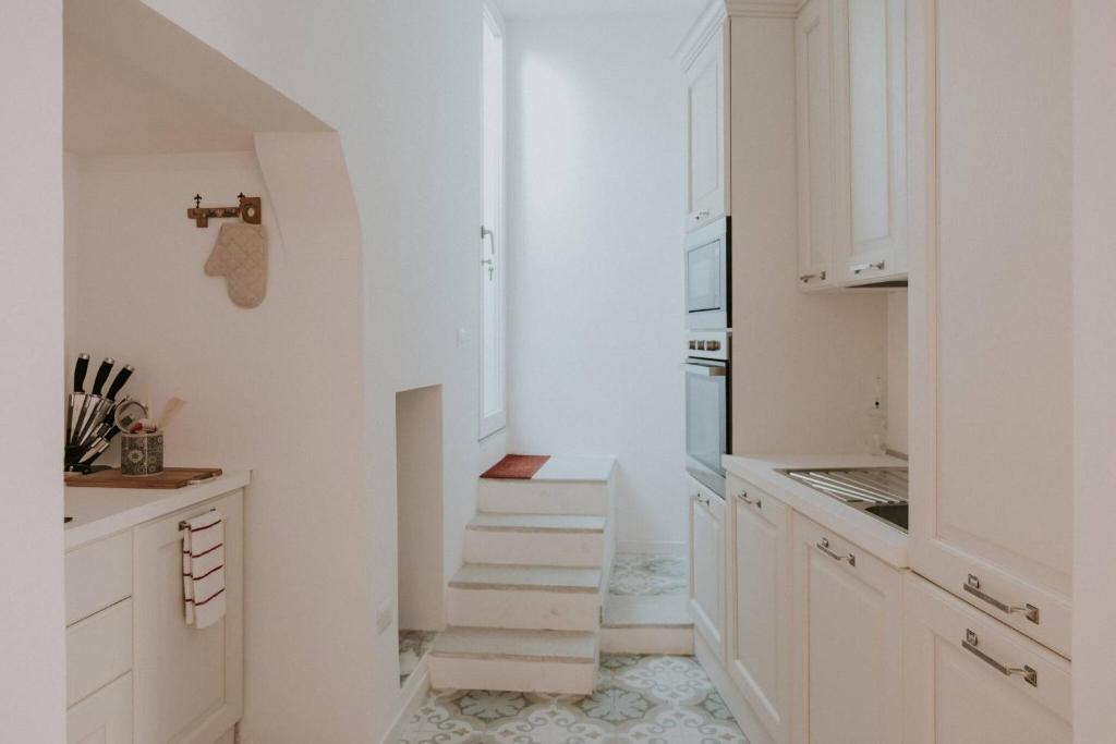 eine weiße Küche mit weißen Schränken und Treppen in der Unterkunft Casa Del Tempio Antico, Salento in Arnesano