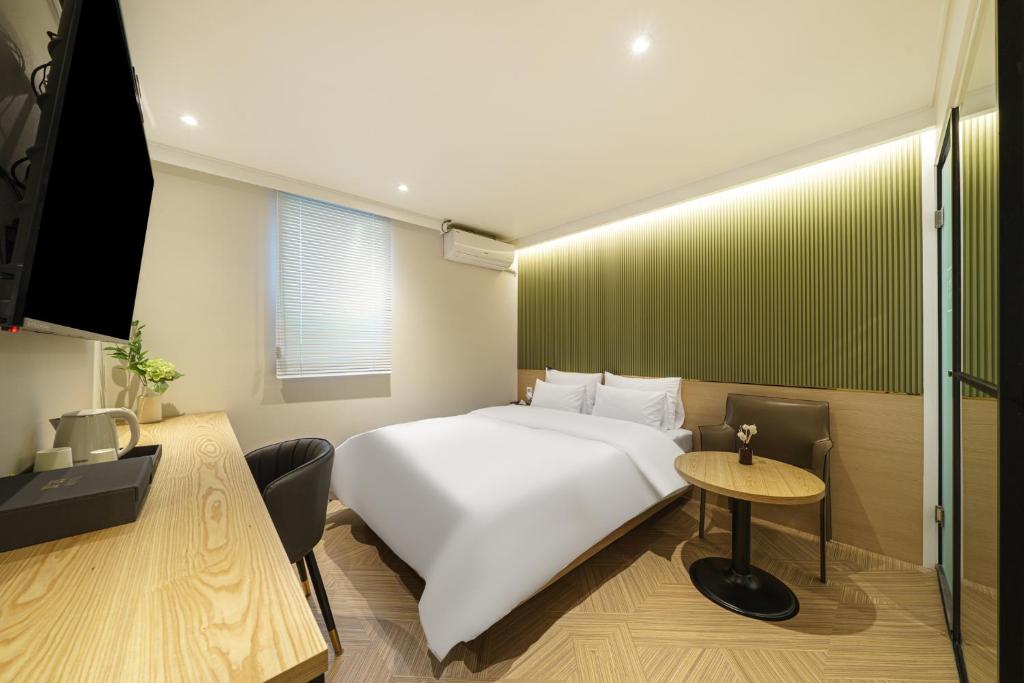 a bedroom with a white bed and a table at No 25 Hotel Dongam Branch in Incheon