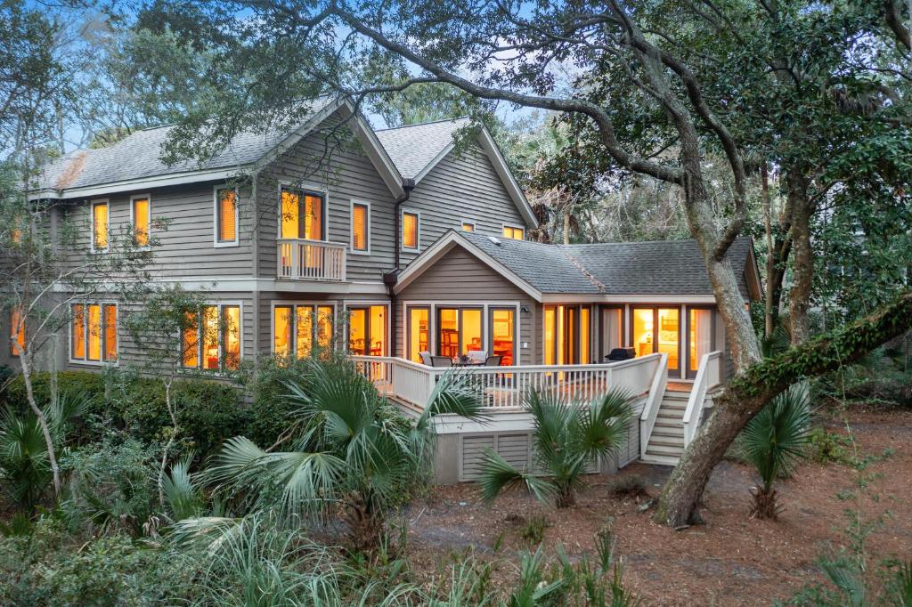 a large gray house with a porch and trees at 152 Augusta National in Kiawah Island