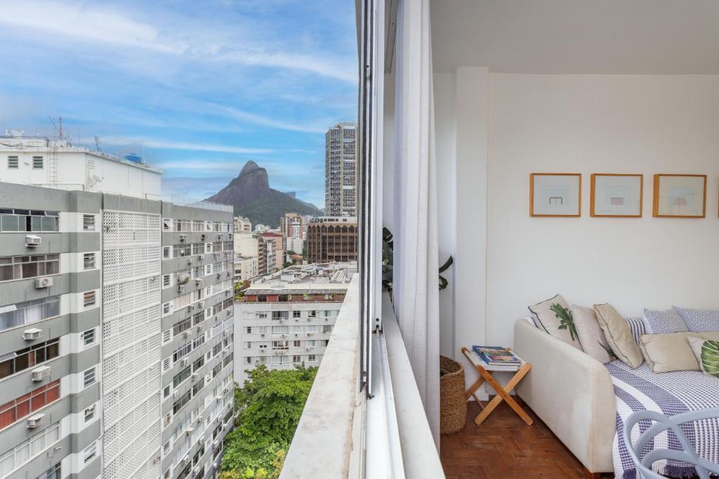 een balkon met een bank en uitzicht op de bergen bij Unhotel - Perfeito Apartamento Temporada no Leblon, Perto da praia in Rio de Janeiro
