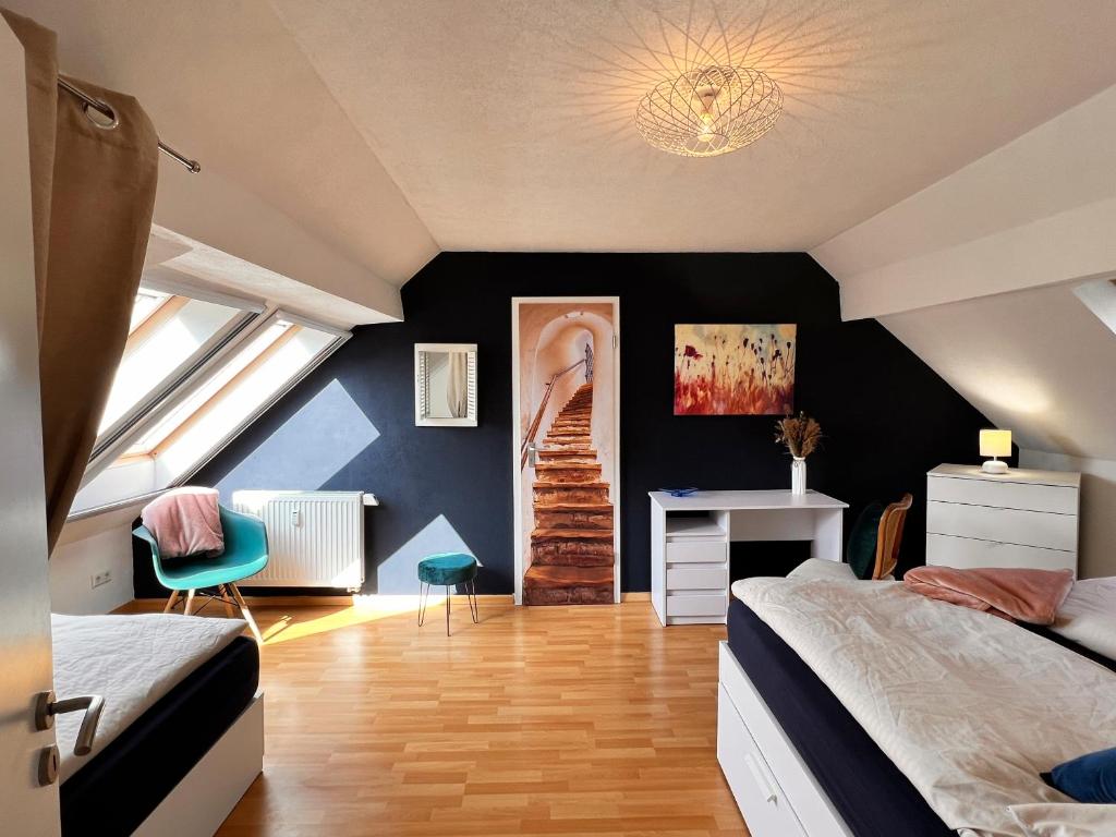 een slaapkamer op zolder met 2 bedden en een bureau bij Ferienwohnung Aurora - Wlan, 2 Schlafzimmer, Küche und Bad in Malterdingen