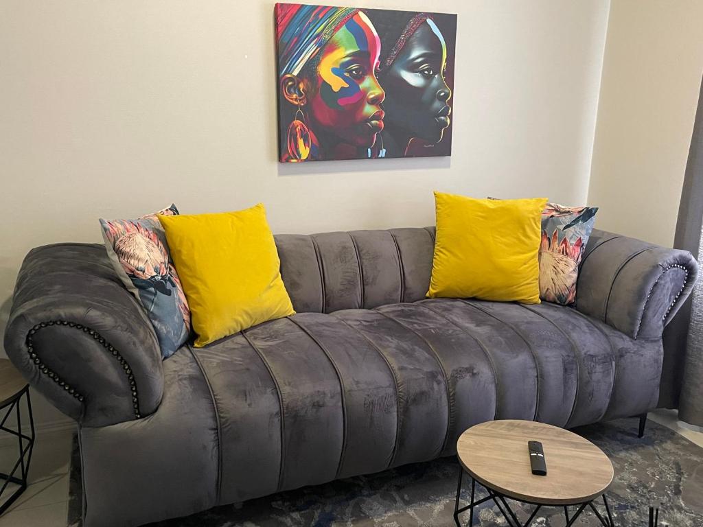 a couch with yellow pillows in a living room at Lovely Cozy Apartment in Midrand