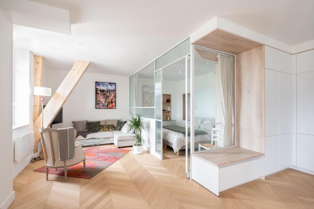 una sala de estar con paredes blancas y suelo de madera. en Les Suites du Bernascon - Appartement 4 étoiles, en Aix-les-Bains