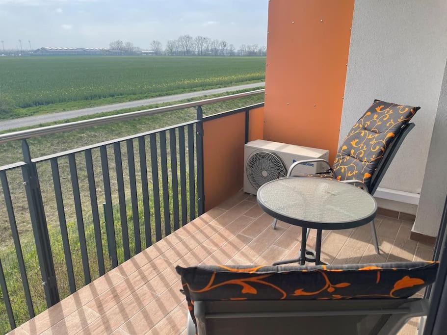 a table and a chair on a balcony with a field at Dvojizbový byt vzdialený 800 m od X Bionic Sphere s dvoma kúpeľňami in Šamorín