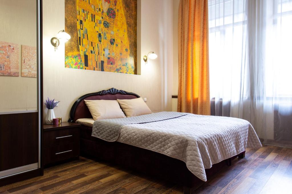 a bedroom with a bed and a painting on the wall at Central District Apartments in Kharkiv