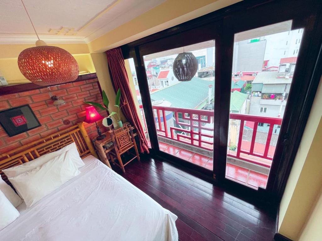 a bedroom with a bed and a view of a balcony at May - Maison De Charme LP in Hanoi