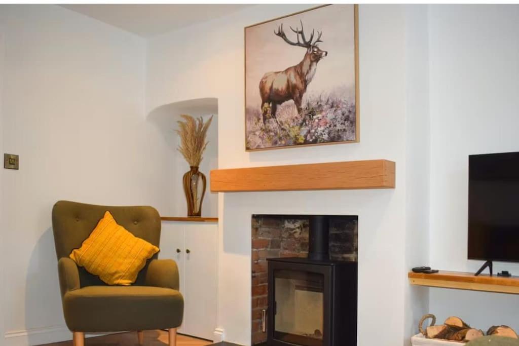 a living room with a fireplace with a picture of a deer at Beautiful renovated cottage in Mersham Ashford Kent in Mersham