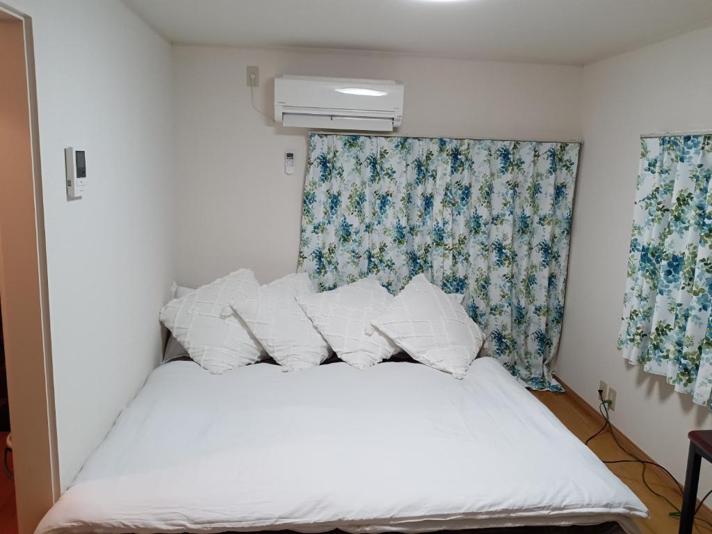1 cama con sábanas blancas y almohadas en una habitación en Tokyo downtown牡丹莊, en Tokio