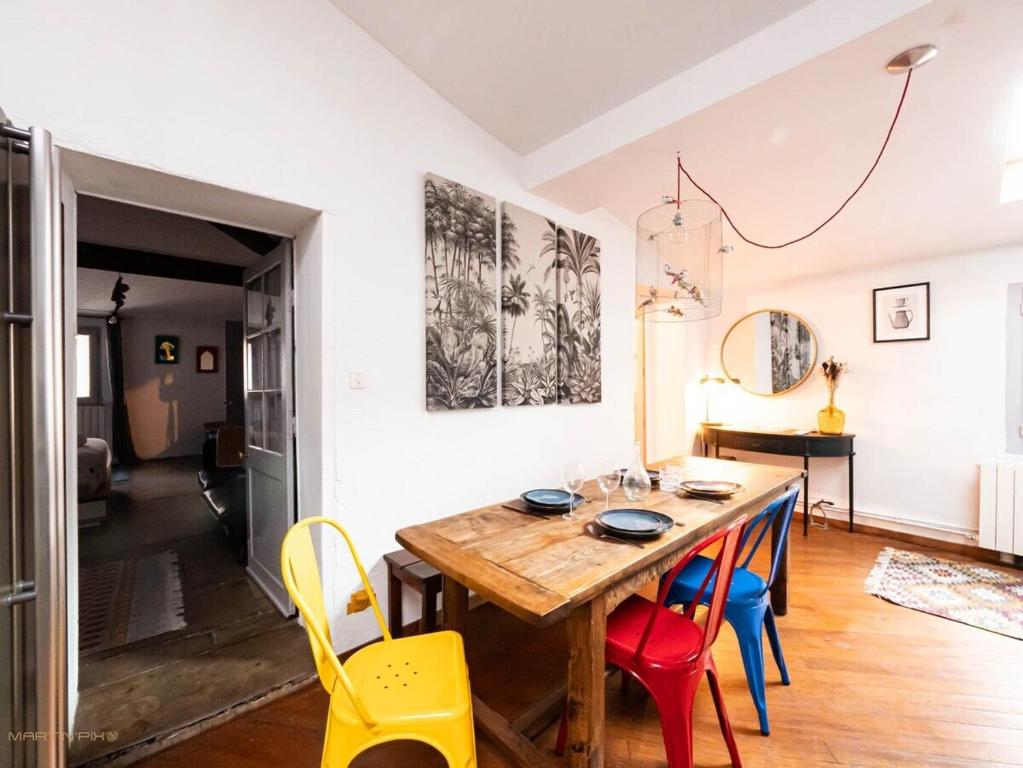 une salle à manger avec une table en bois et des chaises colorées dans l'établissement L'ardoise - Climatisation cœur de ville, à Montpellier