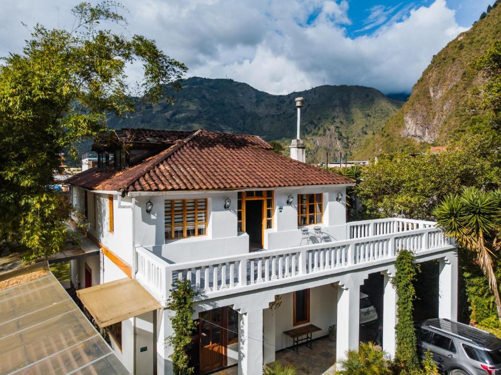 a white house with mountains in the background at 593 Hotel Boutique Baños in Baños