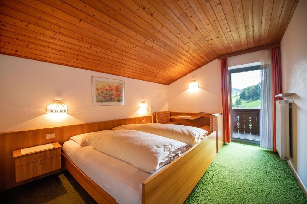 una camera con un grande letto e un soffitto in legno di Alara Rooms a Ortisei
