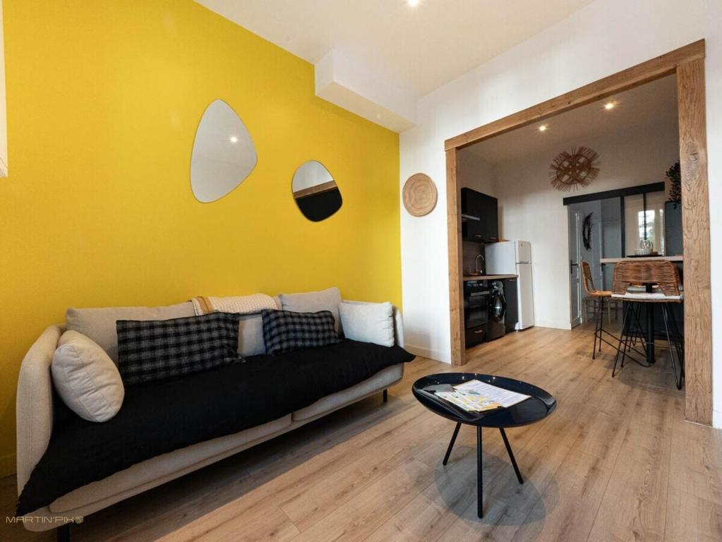 - un salon avec un canapé et un mur jaune dans l'établissement La coquille - terrasse et climatisation en centre ville - gare Saint Roch, à Montpellier
