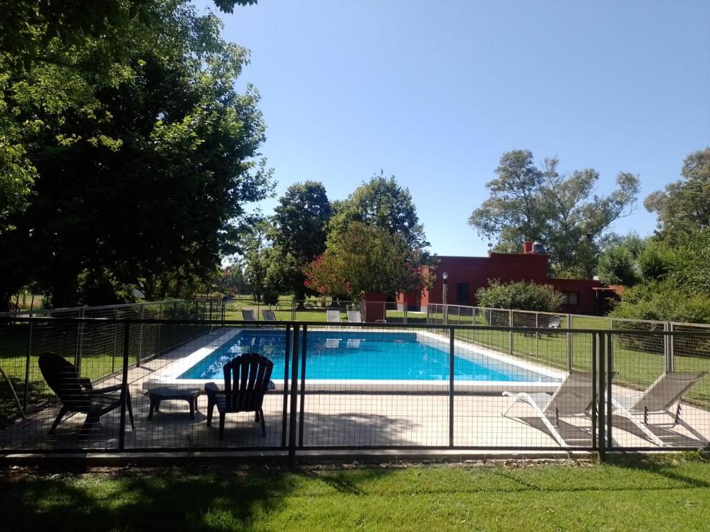 une piscine entourée de chaises et d'une clôture. dans l'établissement La mancha verde casa de campo, à Capitán Sarmiento