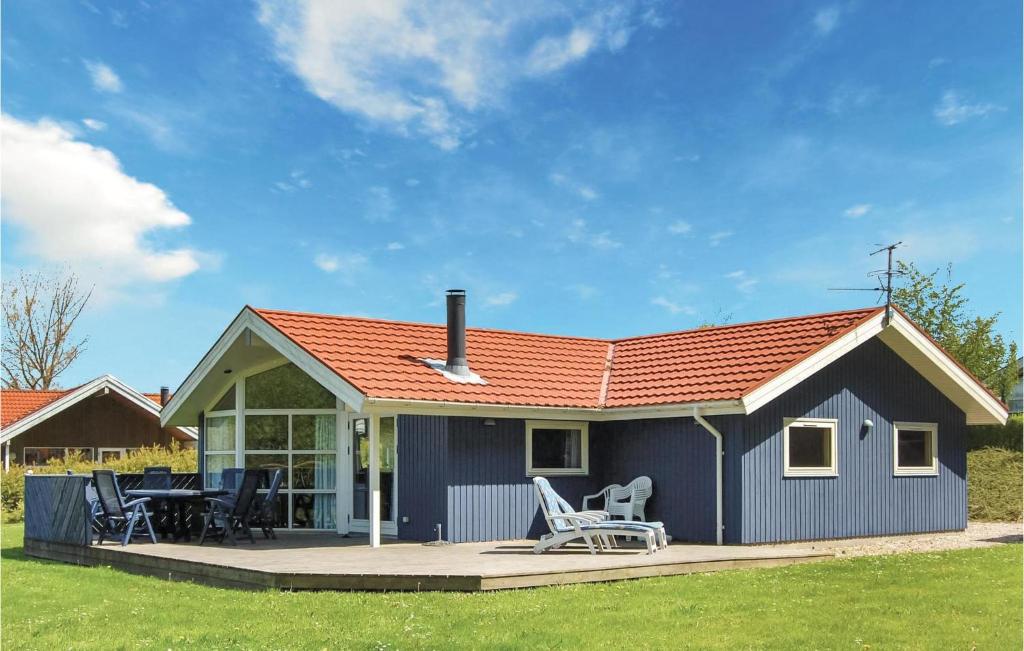Spodsbjergにある3 Bedroom Cozy Home In Rudkbingのデッキ、テーブル、椅子が備わる青いコテージです。