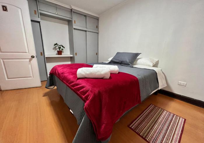 a bedroom with a large bed with a red blanket at Enjoy Budget in Santiago