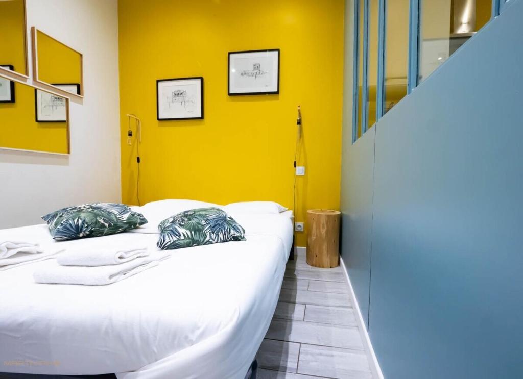 two beds in a room with a yellow wall at Le Jules - Climatisation coeur de ville in Montpellier