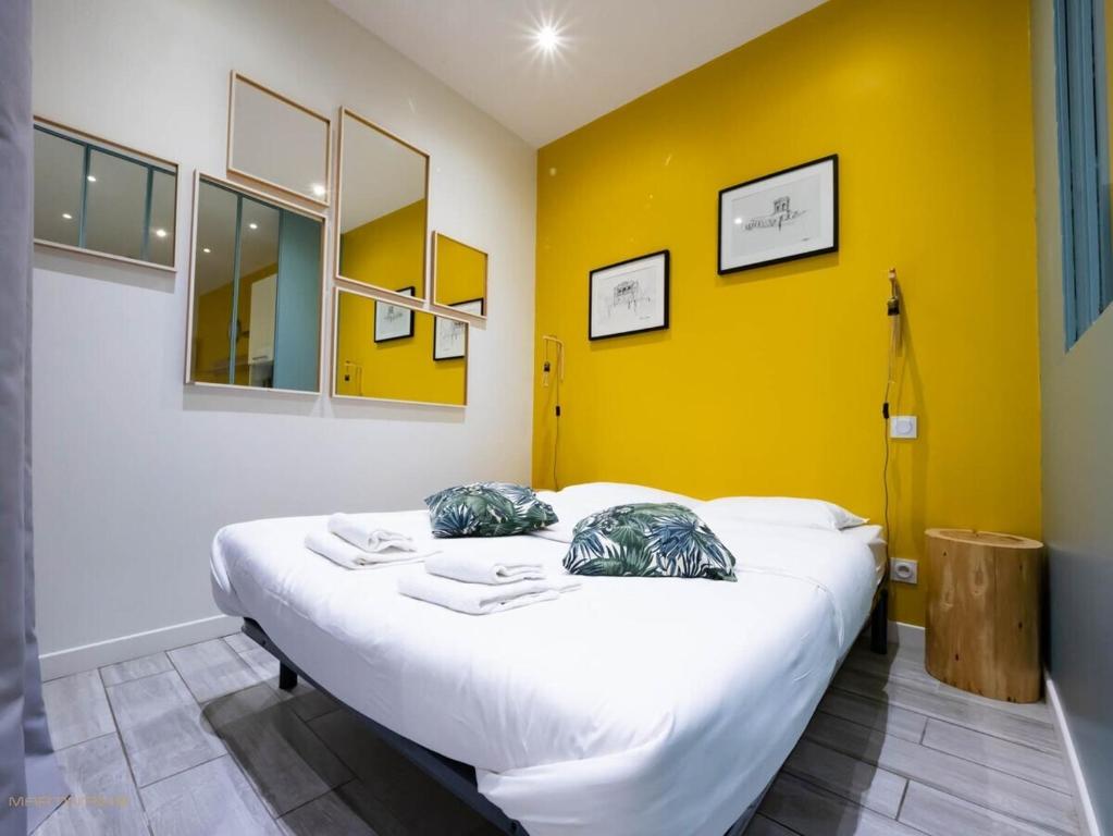 a bed in a room with a yellow wall at Le Jules - Climatisation coeur de ville in Montpellier