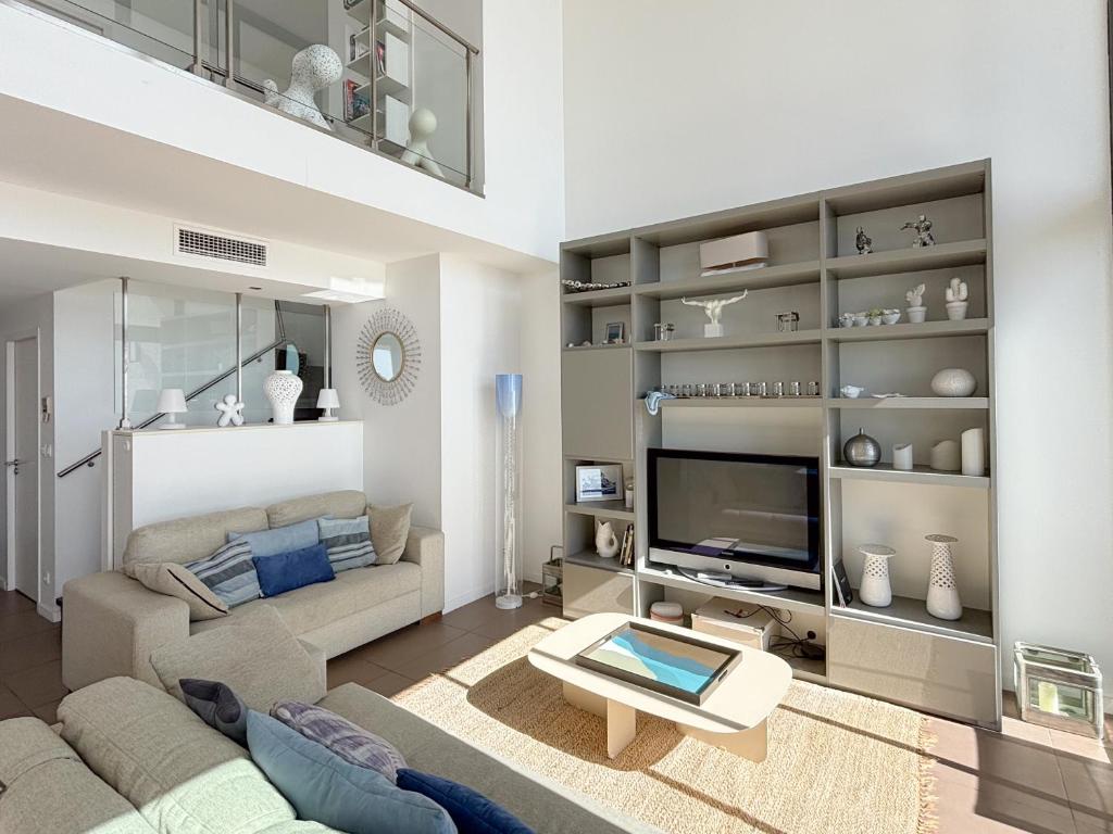 ein Wohnzimmer mit einem Sofa und einem TV in der Unterkunft Entre ciel et mer, Le Murano un séjour de prestige in Sète