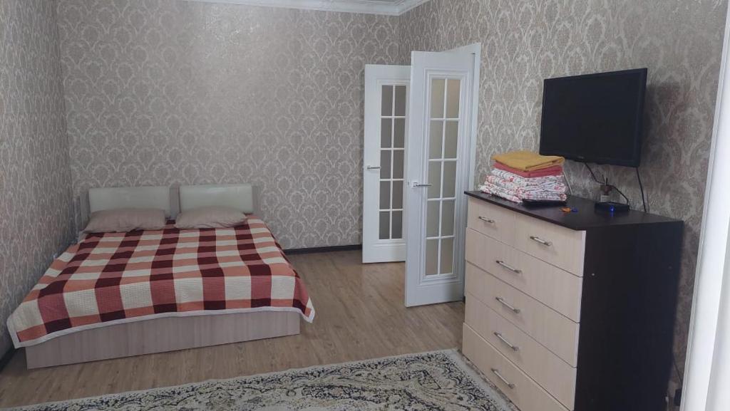um quarto com uma cama e uma cómoda com uma televisão em Imanova 41 em Astana
