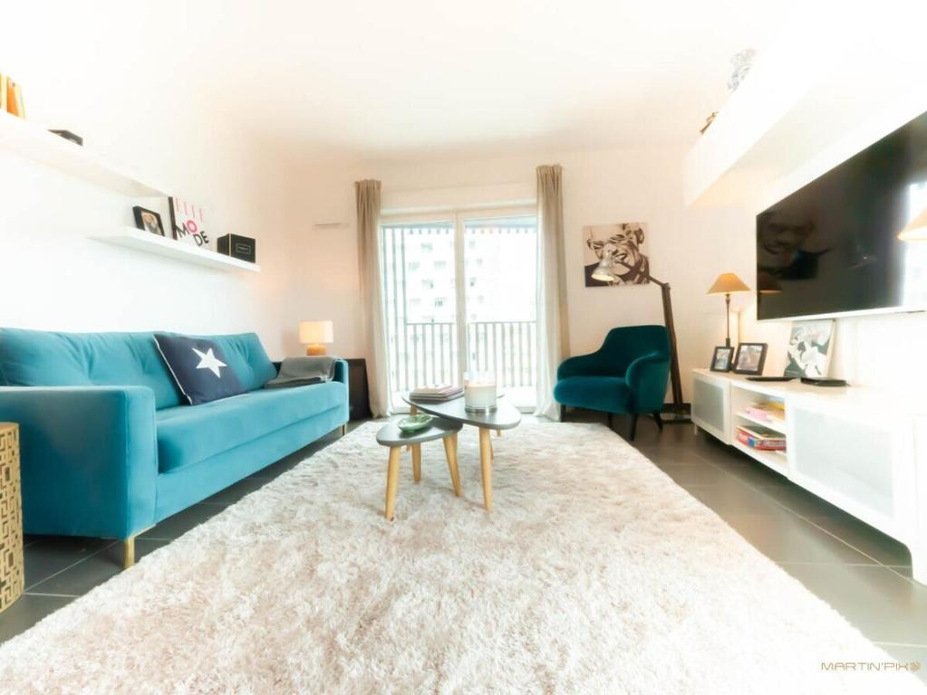 Le Ray Charles - Terrasse - Port Marianne في مونبلييه: غرفة معيشة مع أريكة زرقاء وطاولة