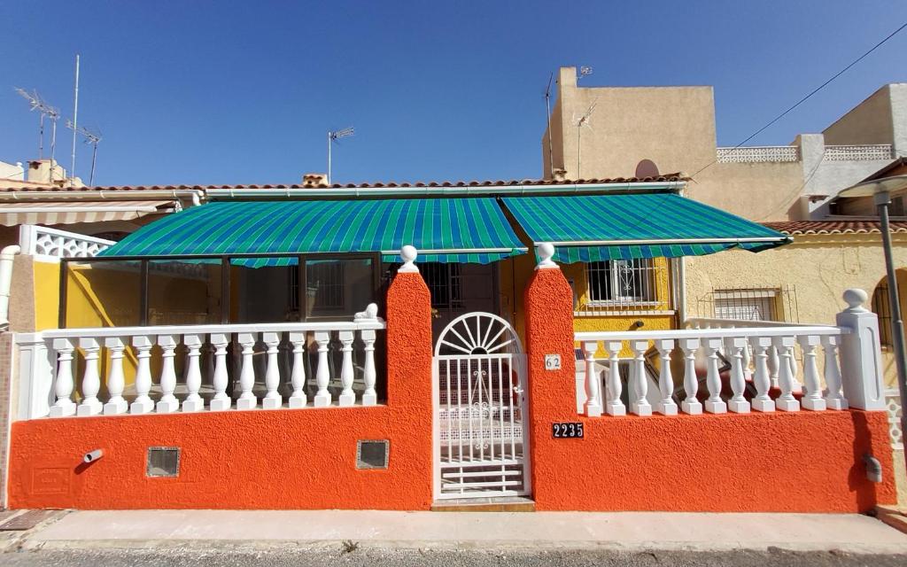ein rotes Gebäude mit einem grünen Dach und einem weißen Zaun in der Unterkunft Haus Mundo La Marina Urbanisation in San Fulgencio