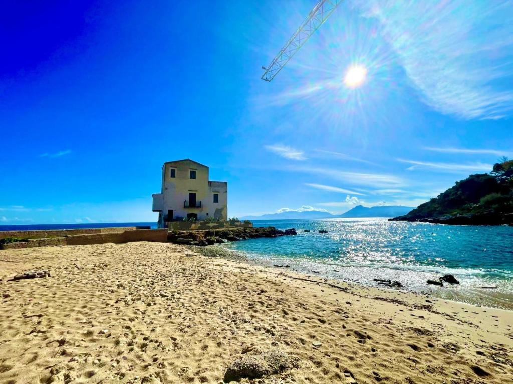 a building on a beach next to the water at Le finestre sul mare in Santa Flavia