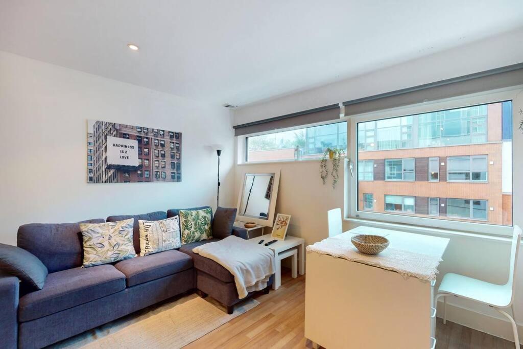 a living room with a couch and a large window at Stunning studio apt- 5 min walk to Borough station in London