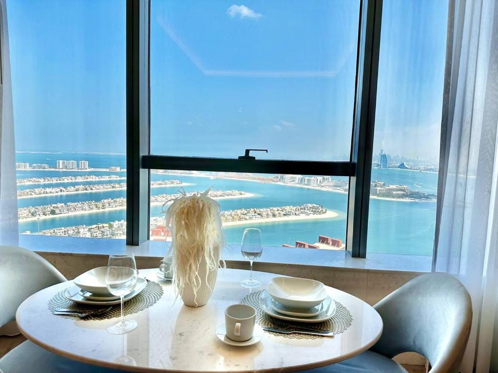 a table with plates and wine glasses in front of a window at Luxury Studio in High Floor Full Sea View in The Palm Tower Plam Jumeirah in Dubai