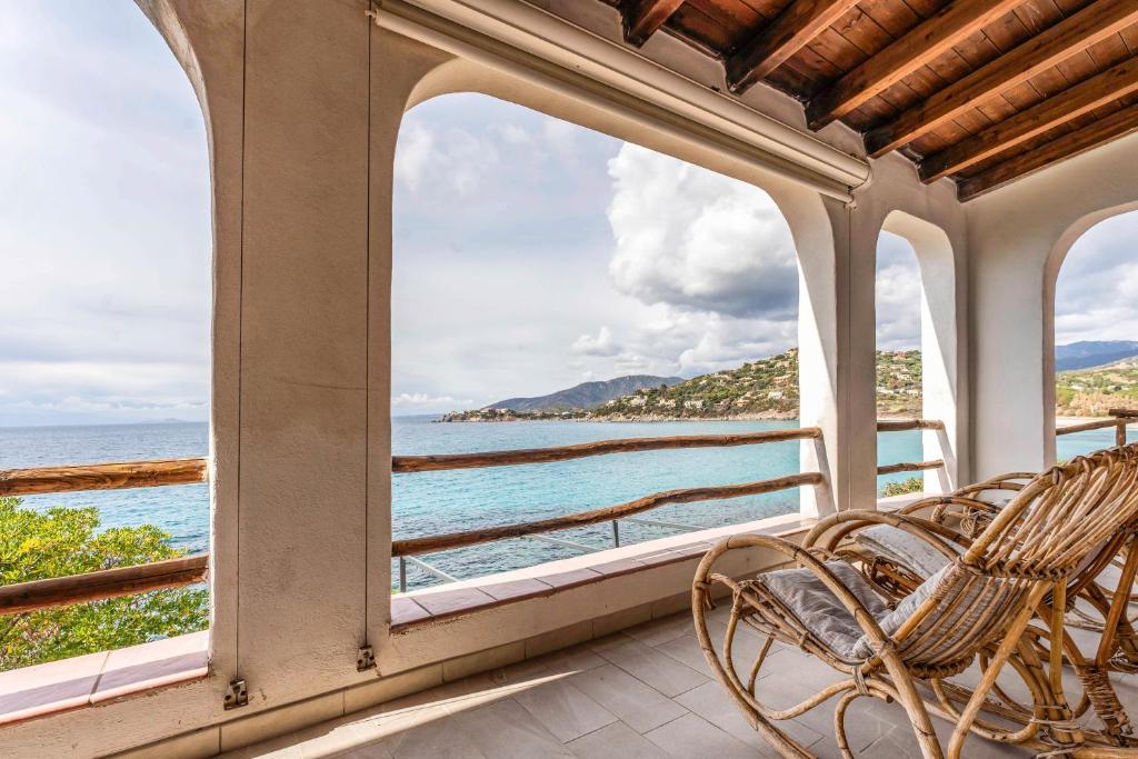 um alpendre com cadeiras e vista para o oceano em Grande Villa Golfo degli Angeli em Torre delle Stelle