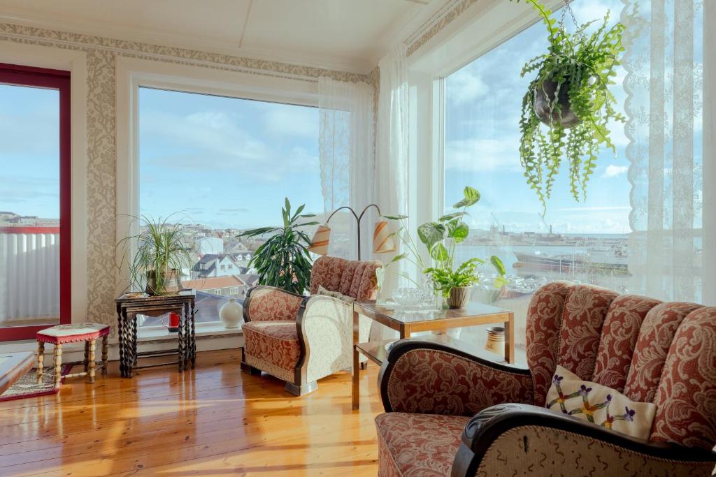 ein Wohnzimmer mit einem Tisch und Stühlen sowie großen Fenstern in der Unterkunft Downtown - Retro Decor - Stunning Views - Terrace in Tórshavn
