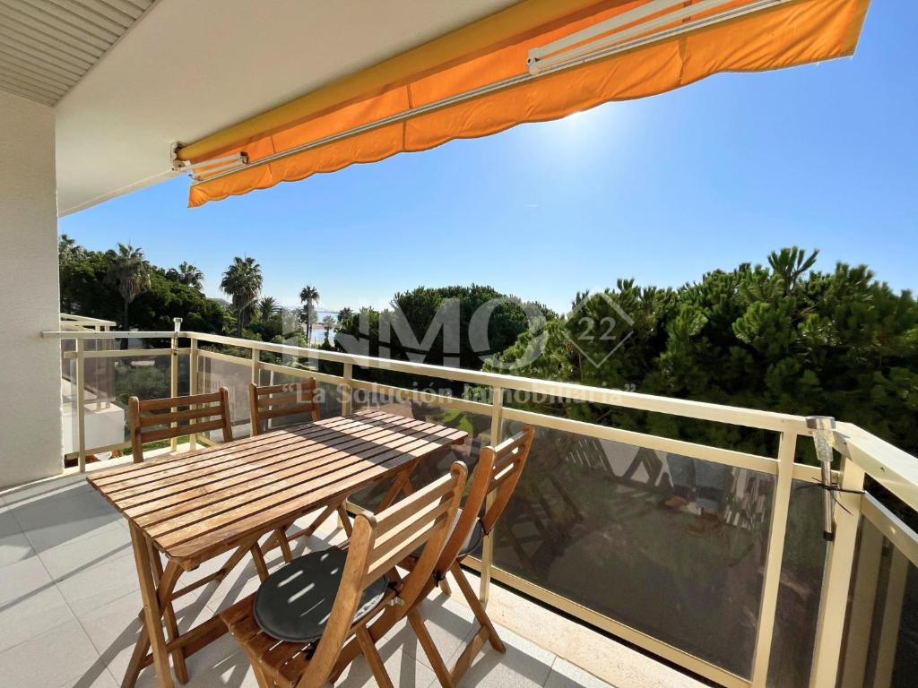 a deck with a wooden table and chairs on a balcony at Apartamento frente al mar en La Llosa Edif Olimpic 103A - INMO22 in Cambrils